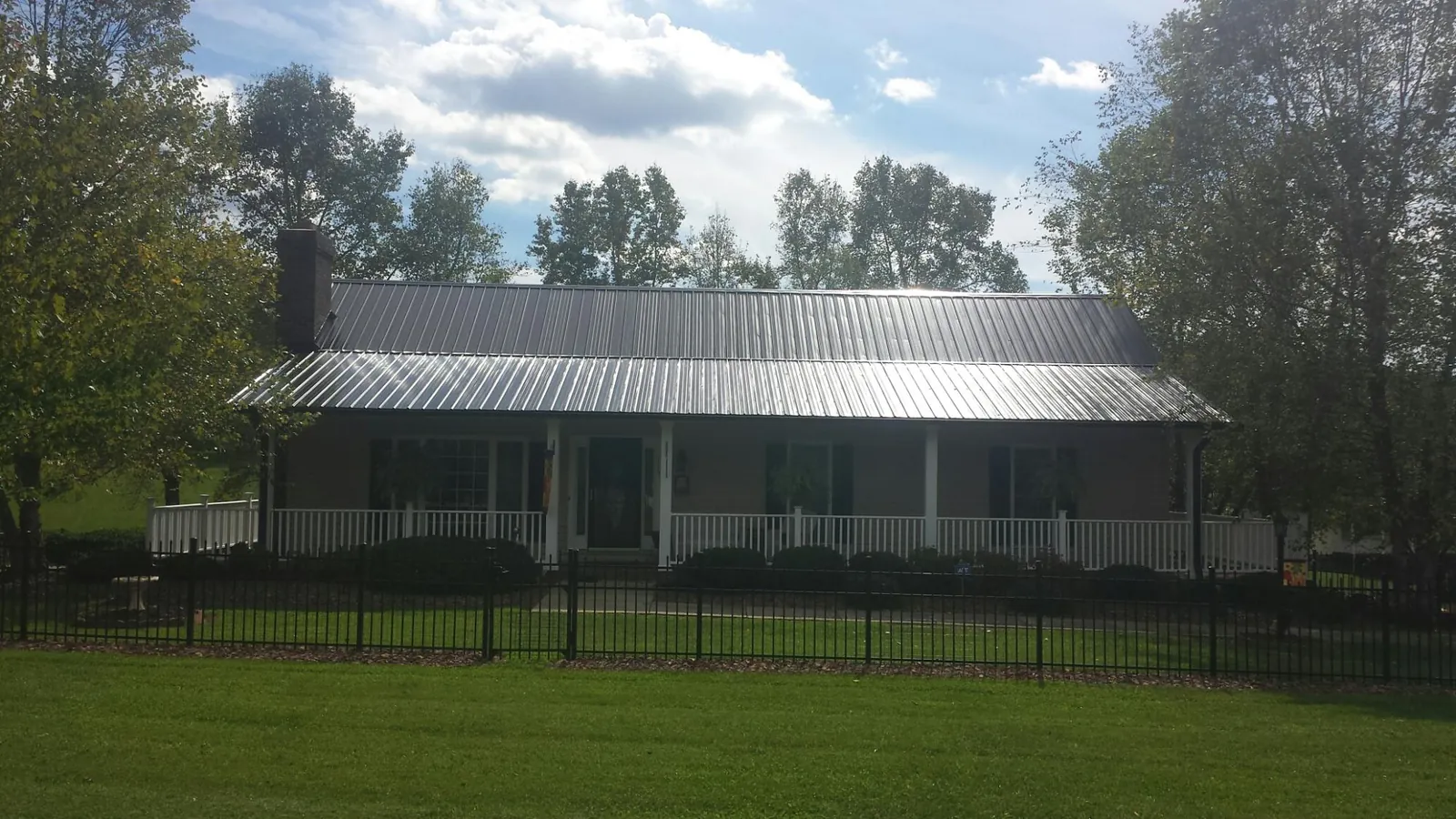 Gray metal roof on a brick ranch with a full width front porch — Gutter Guard Installation work by our crew in Centerville