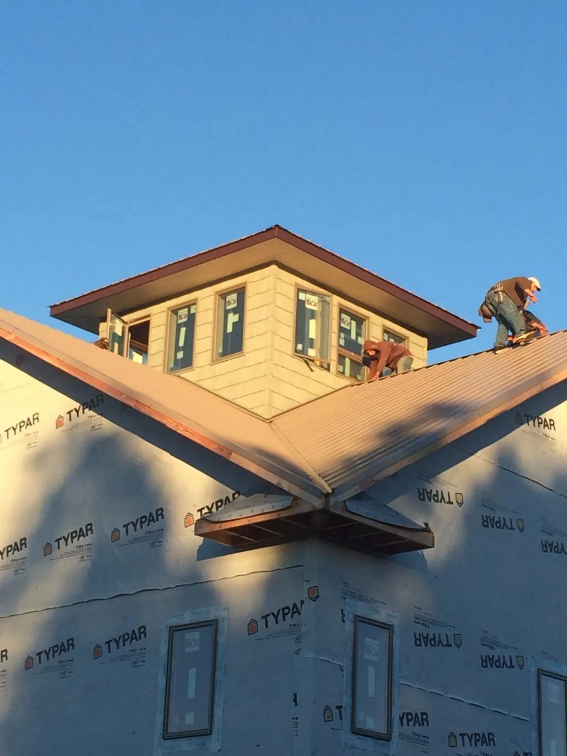 Roofers working around a rooftop cupola on a new metal roof at sunset — Roof Waterproofing in Centerville by Roofing Brothers
